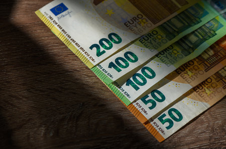 Row of Euro banknotes of various denominations lying on table background, symbolizing finance,...