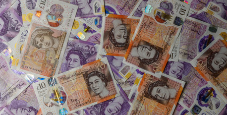 Closeup of 10 and 20 Pound Sterling banknotes spread across table, showing texture, details, and UK currency for finance and banking concept.の写真素材