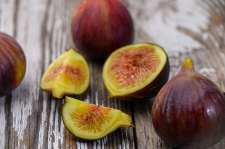 Closeup of ripe figs placed on rustic wooden table in a village, showcasing natural texture,...
