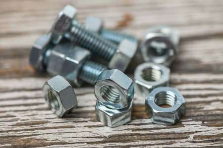 Close-up view of M8 nuts and bolts on a rustic wooden surface, perfect for DIY, industrial, and...