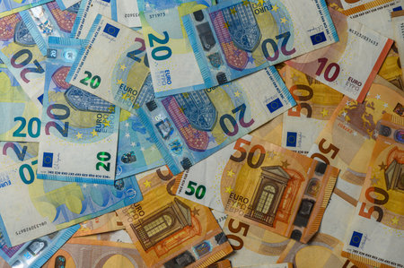 Neatly arranged euro banknotes of various denominations on wooden table, used as background for finance or banking concepts.の写真素材