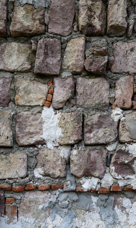 Vertical close-up of old stone masonry. The natural stone texture with cracks and irregularities creates an interesting background for stock photography.の写真素材
