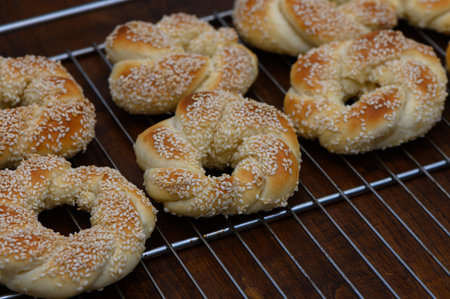 Fresh Turkish bagels simit made at home, arranged on a wooden board. Golden baked goods with...