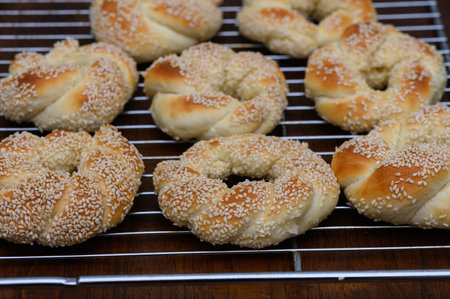 Crispy golden Turkish simit covered with sesame seeds on a rustic wooden table. Traditional Turkish...