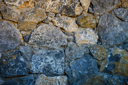 Wall made of natural stone in Cyprus with pronounced texture and natural tones. Perfect as a...