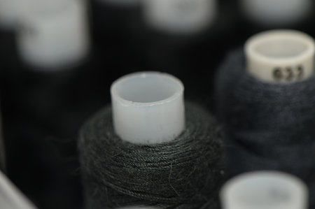 Sewing thread spools arranged in rows, close-up view suitable for tailoring and handmade creative concepts.の写真素材
