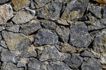 Sunlit stone masonry wall with visible texture and details. Perfect for backgrounds, architectural...