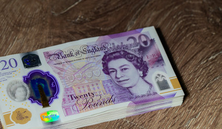 Stack of 20 pound sterling notes on wooden table. Cash, money, and finance concept for stock photography and financial illustrations.の写真素材