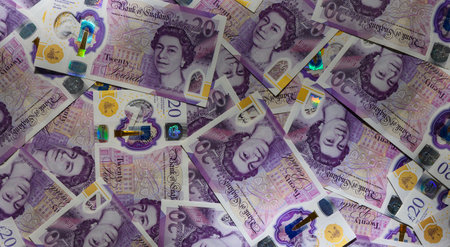 Spread 20 GBP notes scattered on a wooden table. Cash and money concept for stock photography,...
