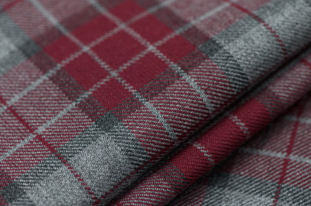Close-up of red tartan fabric in classic Scottish pattern with bright colors and wool texture.の写真素材
