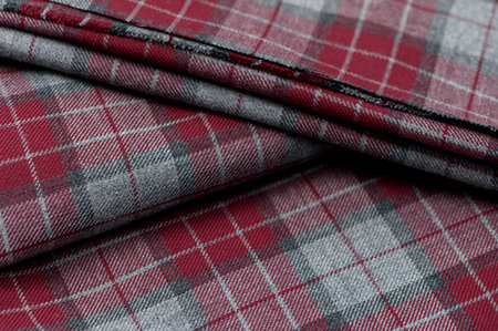 Close-up of bright red fabric with classic Scottish check pattern, detailed texture visible.の写真素材