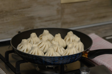 Fresh khinkali cooking on a skillet in the kitchen. Close-up, traditional Georgian dish, tasty homemade food.の写真素材