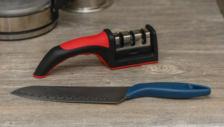 Kitchen knife placed in a sharpener on the table. Close-up, home kitchen, safe knife sharpening.