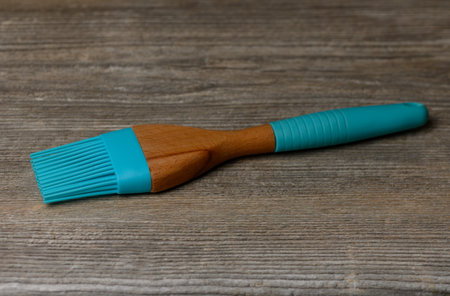 Culinary brush with flexible bristles on old wooden table. Silicone and wood relief contrast forms a practical background for food shoots and culinary blogsの写真素材