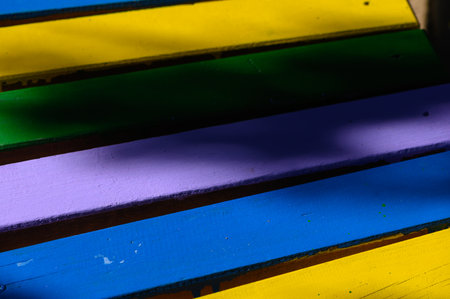 Close-up of colorful wooden planks on a bench. Bright painted wood texture with aged details, creating a cozy and boho-style background perfect for design, food photography, or decoration.の写真素材