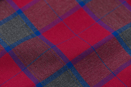 Dense checkered tartan fabric in green, black, and yellow shades. Thread details and surface relief...