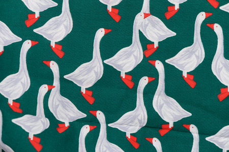 Cotton fabric with cheerful geese in white and yellow tones on bright green background. Cute print and soft texture create a cozy background for kids and kitchen projectsの写真素材