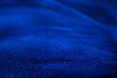 Close-up texture of dark blue fabric. Soft surface with small folds and light reflections, suitable as a background for photography.の写真素材