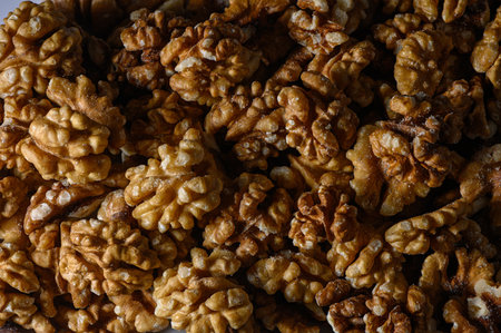 Macro shot of walnut kernels with winding folds, matte and glossy surface in light brown shades. Natural relief and warm light create an appetizing background for cooking, gastro photos, and ads.の写真素材