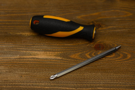Studio shot of screwdriver with rubberized grip and interchangeable double-sided bit cross flat on...