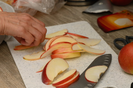Studio shot of woman cutting apples on antique board. Svaneti motifs, warm light, and fresh fruits form authentic backdrop for Georgian recipes and autumn baking.の写真素材