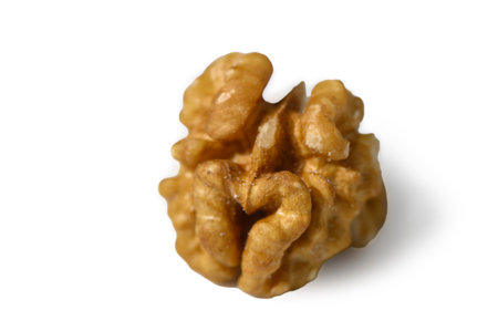 Macro shot of one peeled walnut on white background. Detailed golden-brown texture and appetizing...