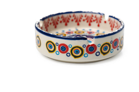 Beautiful ceramic ashtray adorned with the traditional Turkish evil eye (Nazar) pattern. A classic blue amulet used for protection from evil in Turkish culture. Isolated on white background, top view.の写真素材