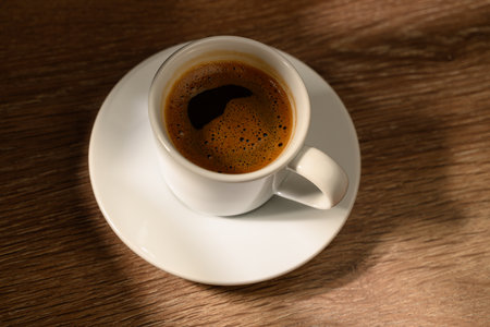 A cup of aromatic Turkish coffee beautifully presented on rustic wooden surface with soft dramatic lighting. Cultural beverage concept with cozy atmosphere.の写真素材