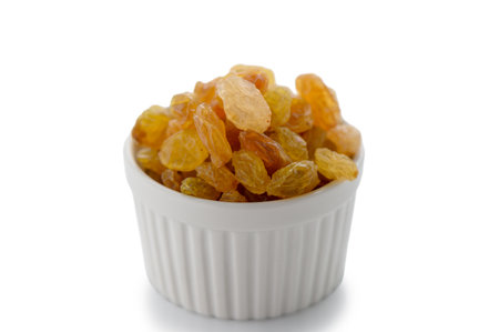 Simple white bowl overflowing with plump golden raisins, professionally photographed on clean white background. Perfect for food and ingredient photography.の写真素材