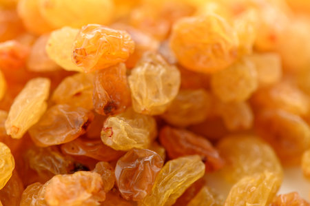 Extreme close-up of appetizing golden raisins. The macro photography reveals intricate wrinkled textures, glossy surfaces, and rich honey-amber tones, making them look juicy and delicious.の写真素材