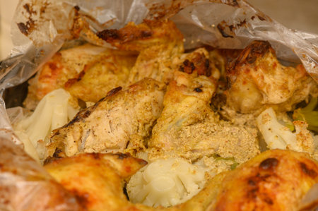 Extreme close-up of juicy oven-bag chicken with broccoli and cauliflower. Details show moist chicken texture, caramelized vegetable edges, and steam rising from freshly cooked dish.の写真素材