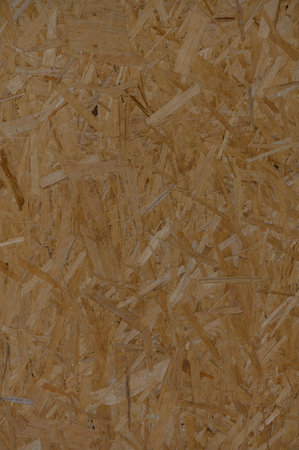 Close-up of OSB board surface with pronounced wood chip texture. Industrial aesthetic and natural...