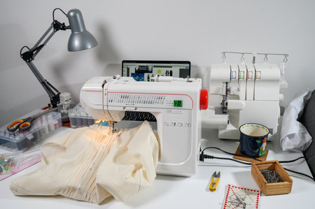 A professional sewing studio setup with an industrial sewing machine, overlocker, and neatly...