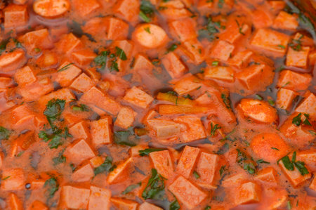 A warm, thick tomato soup packed with soft lentils and savory sausage slices, photographed in an...