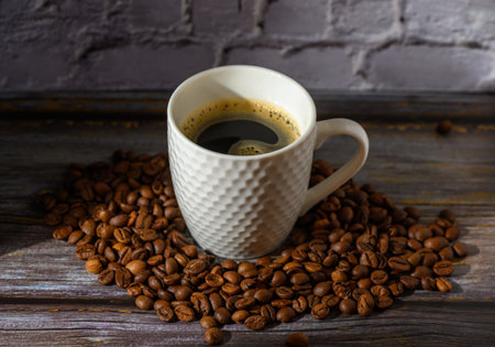 A steaming cup of rich, dark coffee rests amid a circle of aromatic roasted beans on a weathered wooden surface. The soft light highlights the cup's textured surface and the inviting swirls of coffee, creating a cozy, inviting atmosphere.