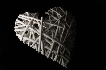 A low key close up of a white wicker heart.の写真素材