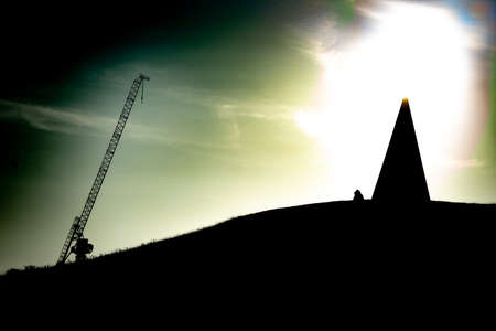 Sunset Silhouette Of Person And Statue On A Hillの写真素材