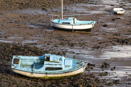 Old fishing boats at low tide on a beachの写真素材