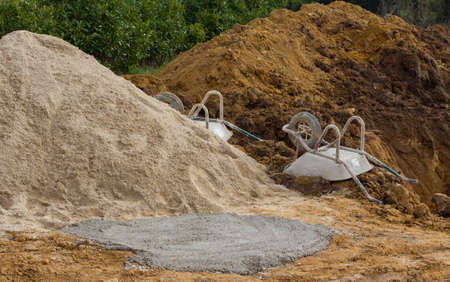 Pile of sand and wheelbarrow on a building siteの写真素材