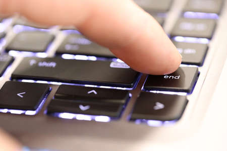finger pushing the end button on a laptop computer key board. The end. the end is near. Stopping,...
