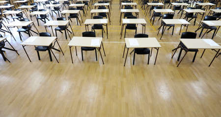 View of large exam room hall and examination desks tables lined up in rows ready for students at a...