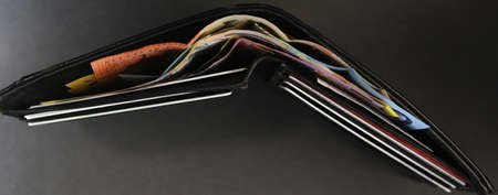 An interesting aerial from above plan view of a black wallet filled with cash dollar notes. Credit...