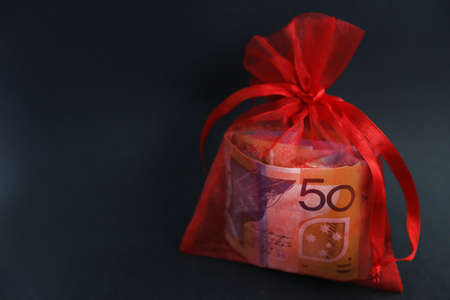 A prettty red glittery bag holding a wad of cash or currency. 50 fifty dollar note clearly visable...