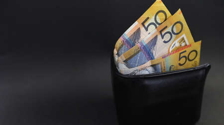 Close up looking down on an isolated black purse or wallet holding 50 fifty dollar notes. Financial budget payday. Personal finances spending a budgeting conceptの写真素材
