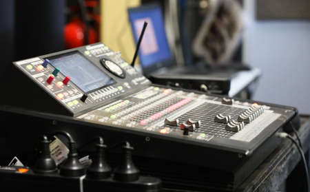 A small sound engineering studio with mixing deck channel mixer and a laptop in the background....