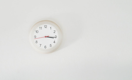clock hanging at the white wallの写真素材