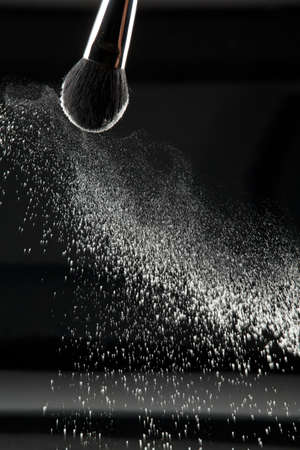 a detail of a powder brush, shaking off white loose powder, shot on black backgrownd.の写真素材