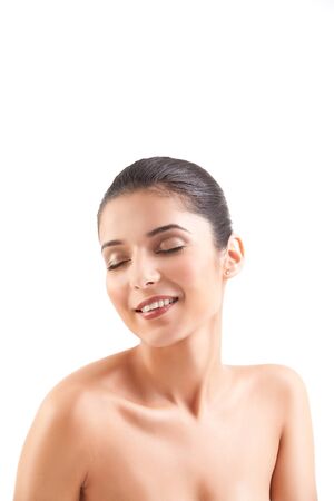 a studio beauty shot of a beautiful woman, with naked shoulders, on white background. her head is turned to the side, her eyes are shut and she is smiling.の写真素材
