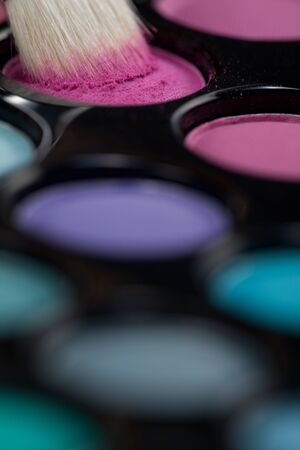 a close-up image of a eye-shadow set, with a professional makeup brush picking up some pink colourの写真素材