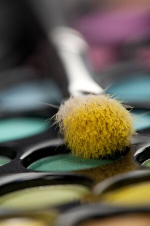 a close-up image of a eye-shadow set, with a professional makeup brush with yellow pigment on itの写真素材